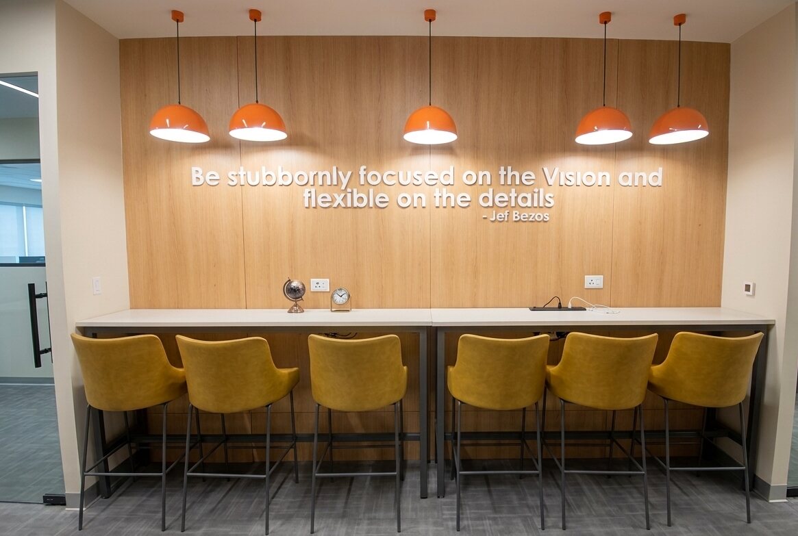 High-bar seating breakout area with pendant lighting and branded wall graphic
